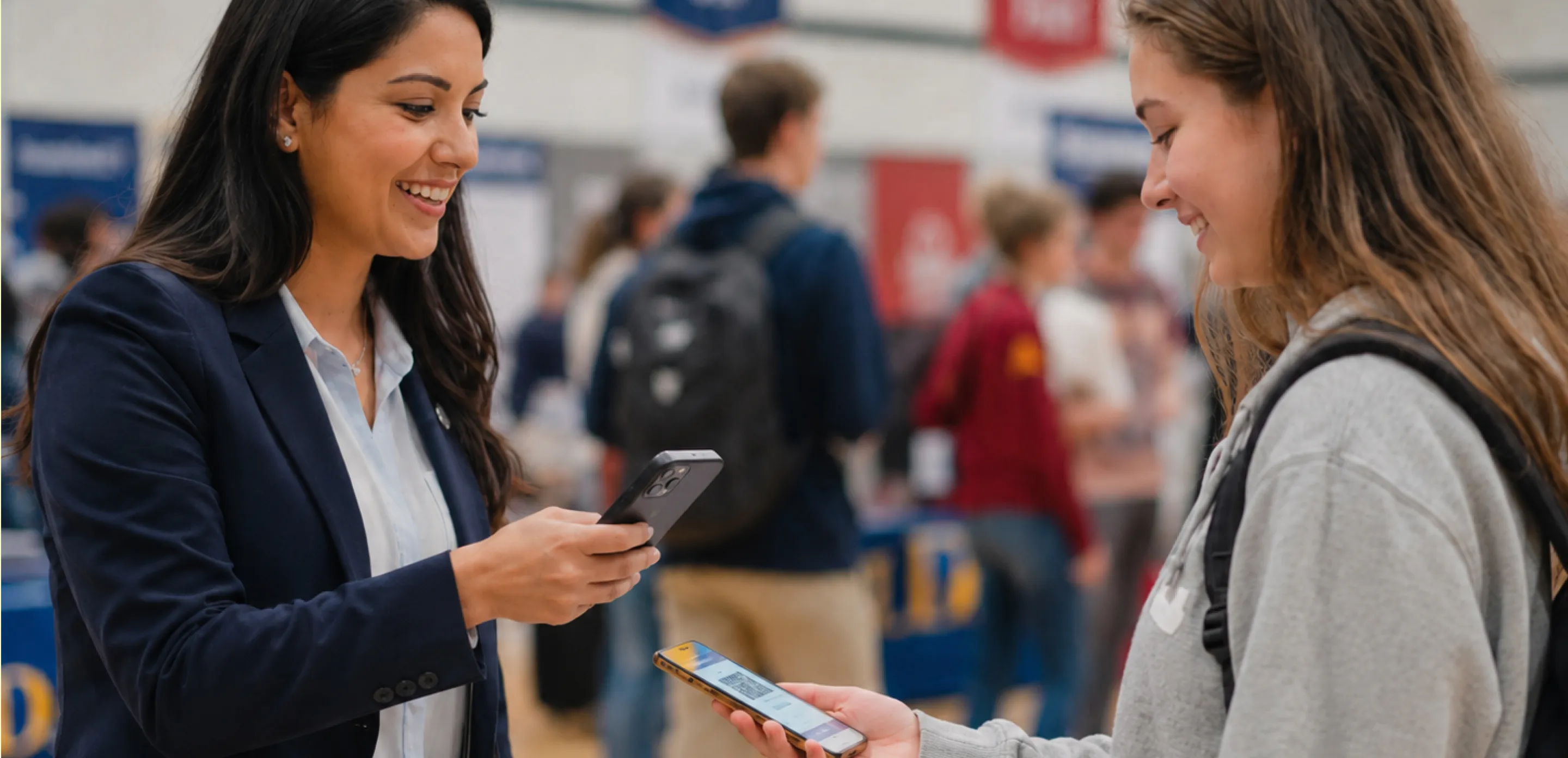 Two students talking at a college fair table